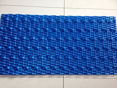 There is one piece of special cooling tower fill on the ground, it is blue and has uniform raised points.